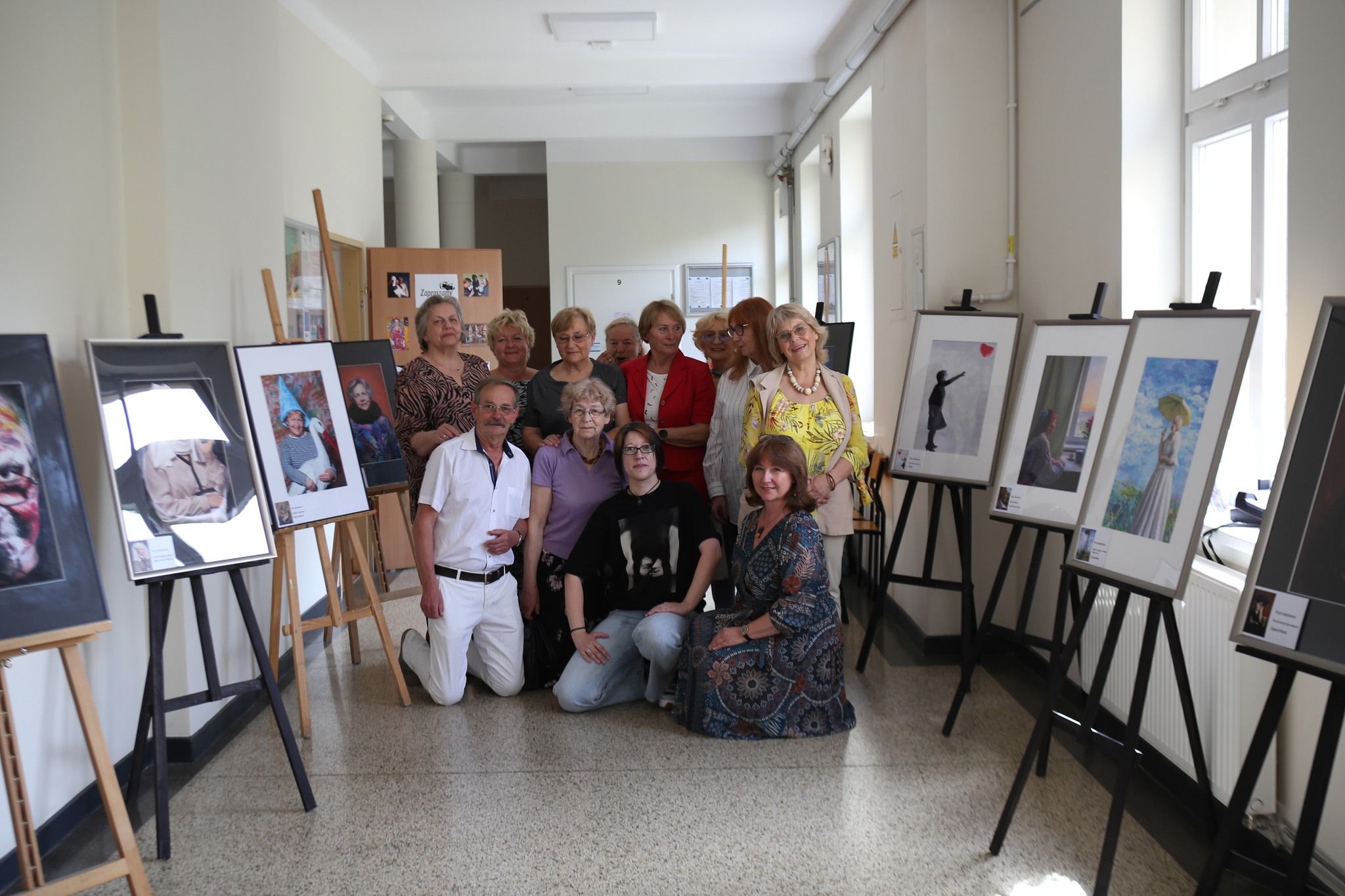 Grupa ludzi otaczająca się pracami